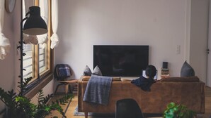 Olohuone, jossa on sohva, televisio ja ikkuna, jossa on verhot.