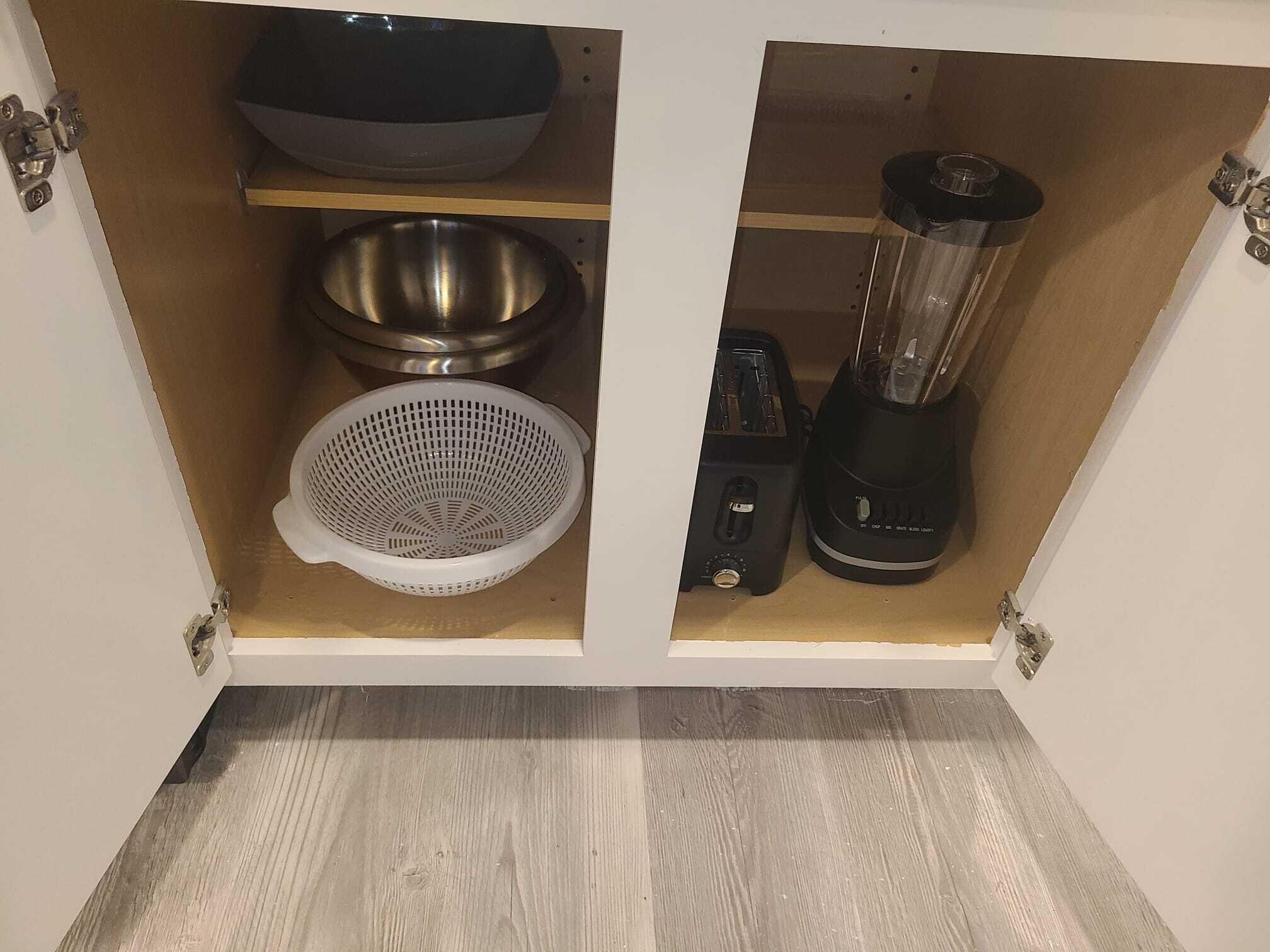 Une cuisine équipée d’un évier en acier inoxydable, d’une passoire, d’un mixeur et d’un grille-pain.