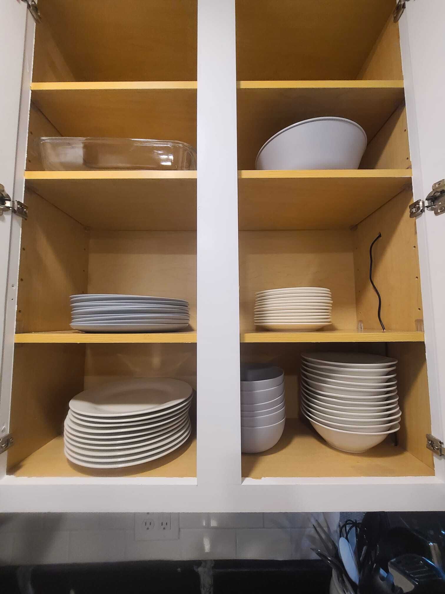 A cabinet with shelves holding stacks of plates and bowls.