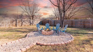 A backyard with a fire pit, four Adirondack chairs, and a wooden fence. - Instant Book, Clean & Cozy - minutes to Kalahari (Round Rock)