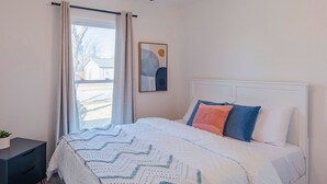 A bedroom with a bed, a ceiling fan, a window with curtains, and a painting on the wall. - Instant Book, Clean & Cozy - minutes to Kalahari (Round Rock)