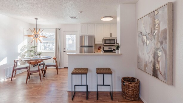 A modern kitchen with white cabinets, stainless steel appliances, and a bar area with stools. - Instant Book, Clean & Cozy - minutes to Kalahari (Round Rock)