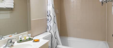 A bathroom with a sink, toilet, and bathtub. There are towels on a rack and a shower curtain.
