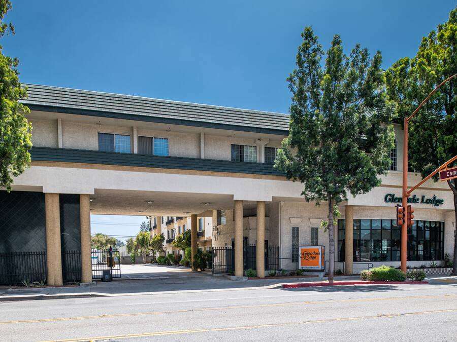 Un hotel con entrada cubierta, un letrero que dice "Glendale Lodge" y vista de la calle con un semáforo.