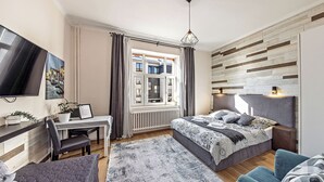 Un dormitorio moderno con cama, escritorio y televisor.
