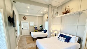 Une chambre d’hôtel avec deux lits, une maquette de bateau accrochée au mur et une décoration sur le thème des bateaux.
