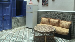 Een kamer met een patroon vloer, een bank met bloemenkussens, een kleine tafel en een koelkast.