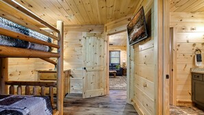 Un interior de madera con literas, una puerta que da a otra habitación y una zona de cocina.