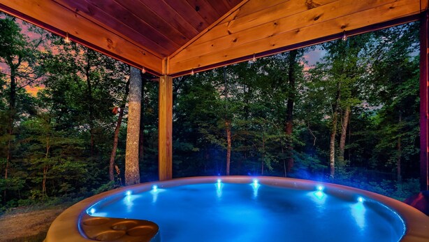 Un jacuzzi con techo de madera y vistas a un área boscosa.