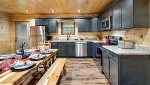 Una cocina moderna con techo de madera, electrodomésticos de acero inoxidable y encimera de granito.