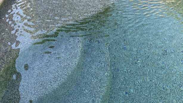 Une piscine en pierre, bordée de pierres, avec des marches menant à l’eau.
