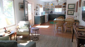 A spacious living room with a dining area, kitchen, and a large window providing natural light. - CanalHouse Private Large Home on Canal Front (Ocracoke)