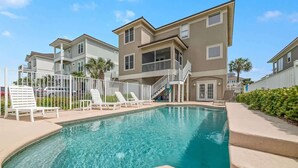 A swimming pool with lounge chairs and a staircase leading to a building with balconies. - Ocean Terrace-Large beach house with private pool (Gulf Shores)