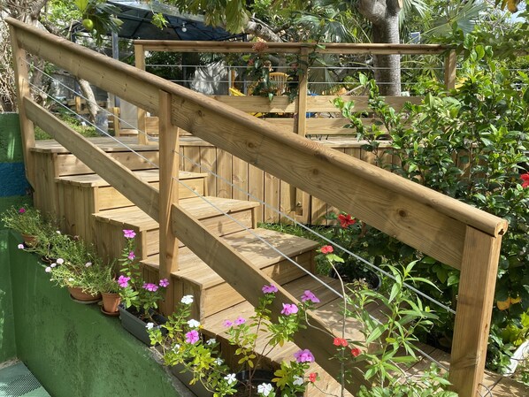 Escada de madeira com corrimão, cercada por vasos de plantas e flores.