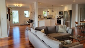 A modern living room with a grey sectional sofa, a glass coffee table, and a dining area with a small table and chairs. - Oakton St. Inn, Evanston near Northwestern, Loyola and Chicago (Evanston)