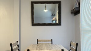 Un comedor con una mesa y sillas de madera, un espejo montado en la pared y un reloj.