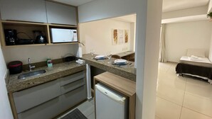 A compact kitchen with a microwave, coffee maker, and a small refrigerator. - Bela Hospedagem - Marinas Cabo Branco (João Pessoa)