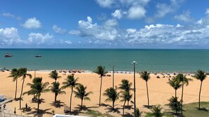 A beach with palm trees, a sandy shore, and the ocean. - Bela Hospedagem - Marinas Cabo Branco (João Pessoa)