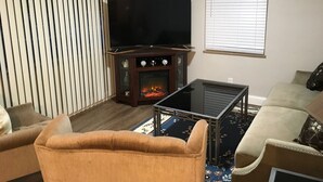 Ein Wohnzimmer mit Flachbildfernseher, Kamin, Sofa und Couchtisch.
