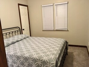 Un dormitorio con cama, puerta y ventana con persianas.