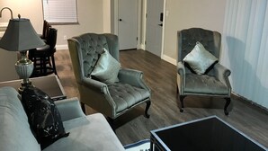 Ein Wohnzimmer mit zwei Polstersesseln, einer Couch, einer Lampe und einem Couchtisch.