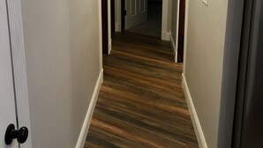 Ein Flur mit Holzboden, weißen Wänden und einer Tür am Ende.