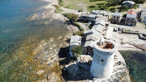 Ein Küstdorf mit Steinhäusern, einem markanten Leuchtturm und klarem Wasser.
