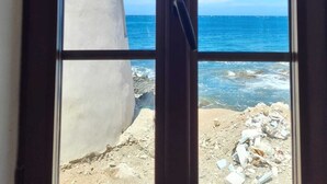 Blick durch ein Fenster auf einen klaren, blauen Himmel und den Ozean.