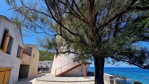 Ein Küstenhaus mit einer Steintreppe, die zu einem Holzdeck mit Blick aufs Meer führt.