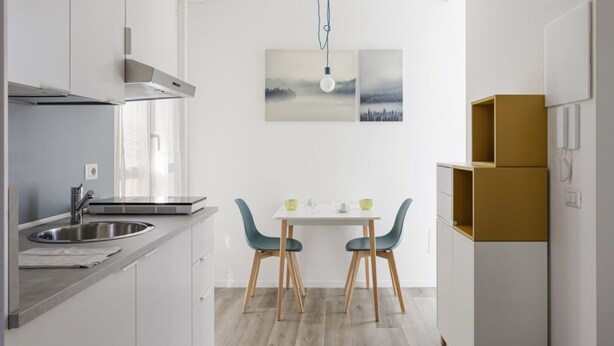 Una cocina moderna con comedor, electrodomésticos de acero inoxidable y un diseño minimalista.
