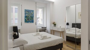 Ein modernes Schlafzimmer mit Bett, Nachttisch, Schreibtisch, Stuhl und einem großen Spiegel.