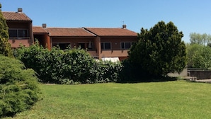 A two-story house with a red-tiled roof, surrounded by a well-maintained lawn and dense shrubbery. - Simona apartment near Lake Garda and Verona (sona)