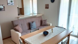 A modern living room with a sofa, a dining table, and a kitchen area. - Simona apartment near Lake Garda and Verona (sona)