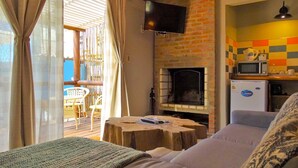 A cozy room with a fireplace, a television, and a kitchenette. - Il Tano Suites Punta del Diablo (Punta del Diablo)
