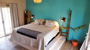 A bedroom with a bed, bedside lamps, a potted plant, and a window. - Il Tano Suites Punta del Diablo (Punta del Diablo)