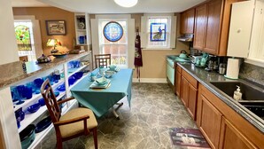 A kitchen with a dining table, chairs, a stove, and various kitchen appliances.