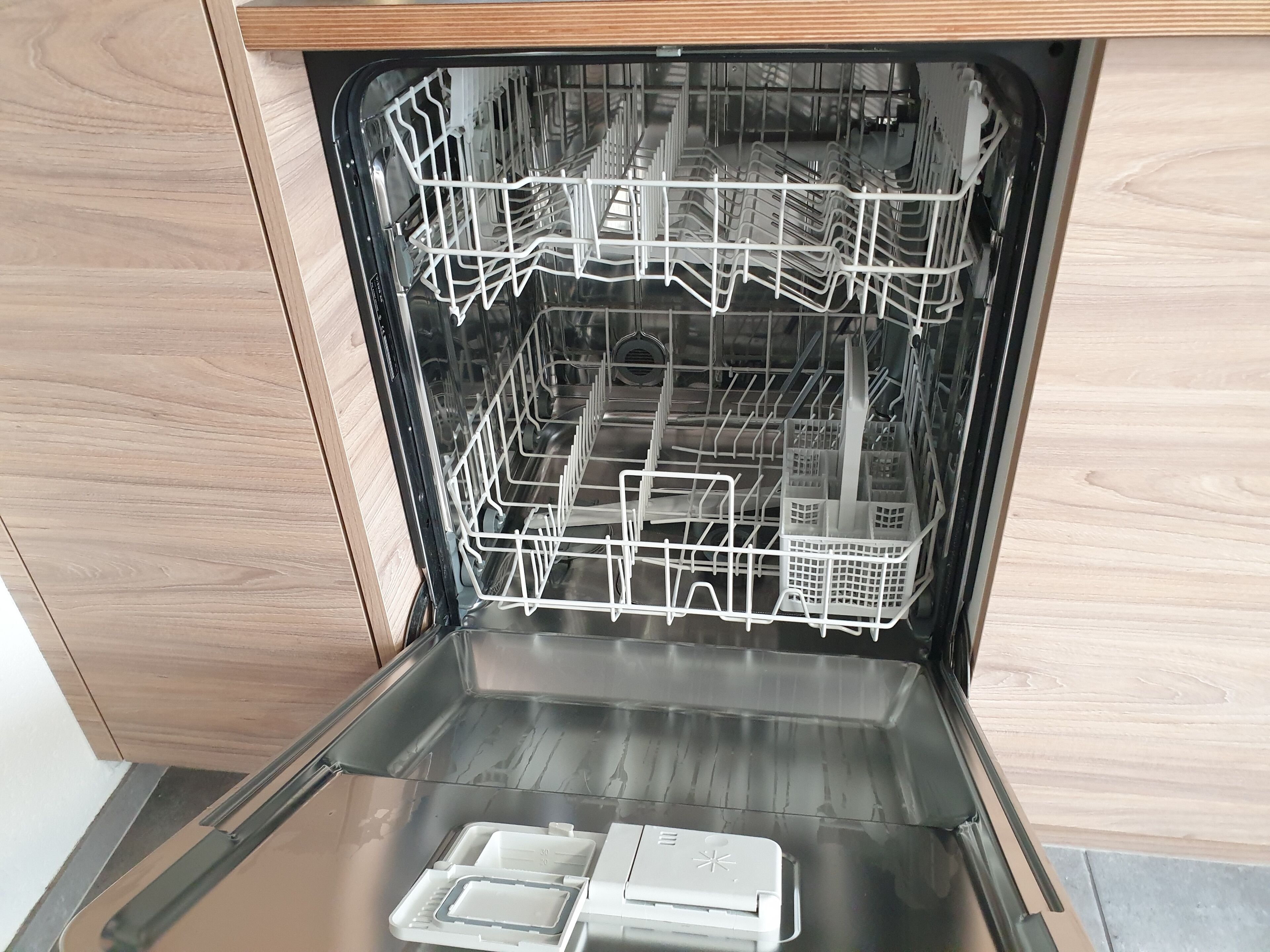 An open dishwasher with multiple racks and a control panel.