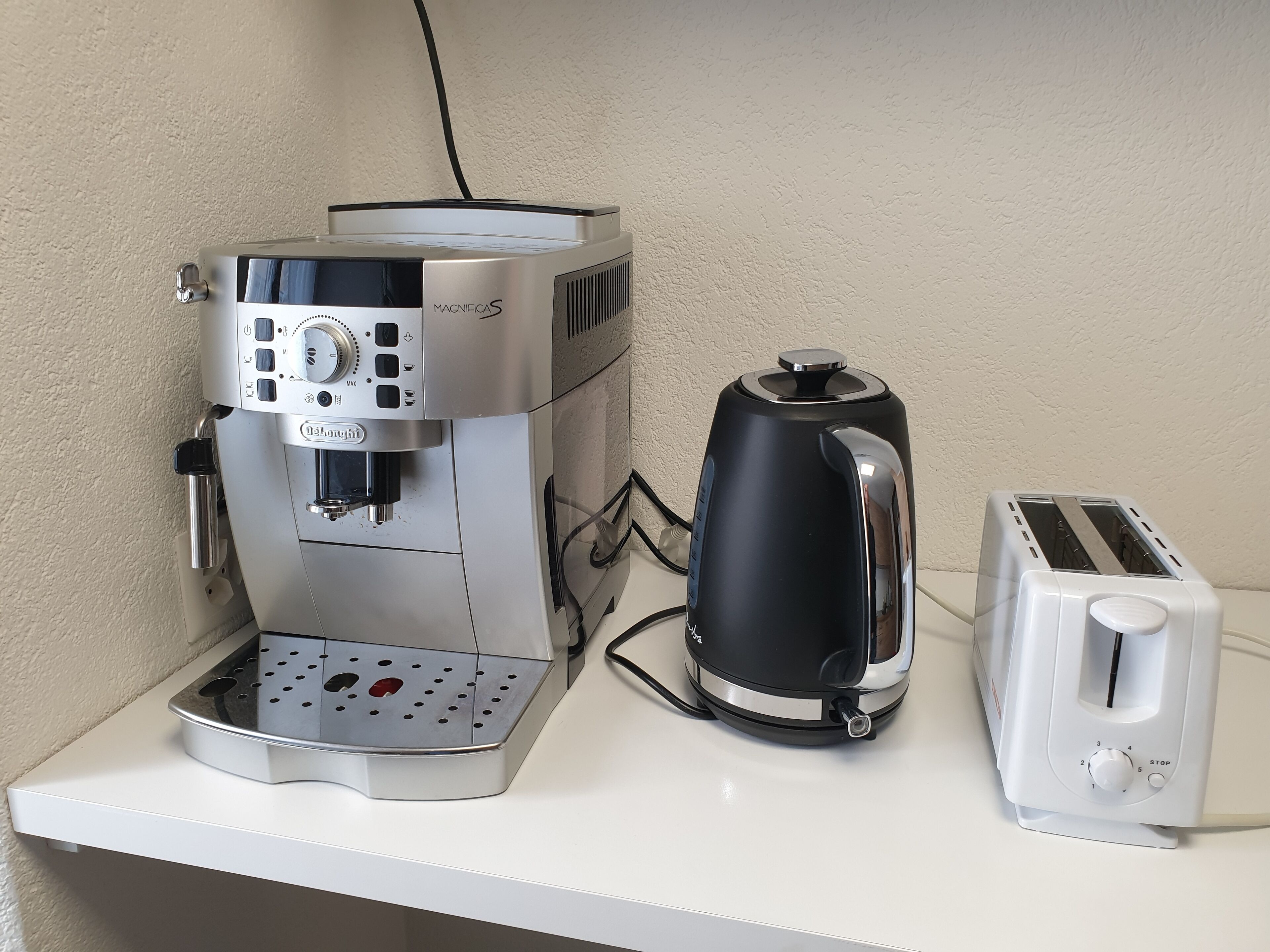 A coffee maker, a kettle, and a toaster on a white countertop.