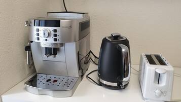 A coffee maker, a kettle, and a toaster on a white countertop.