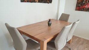 A dining table with four chairs, a vase, and abstract art on the walls. - "VILLA HI" apartment parking space included  (Weesen)