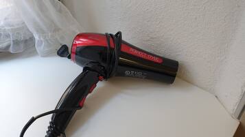A hair dryer with a red and black design, placed on a white surface.