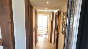 A hallway with a wooden floor, a red patterned rug, and a door on the right. - "VILLA HI" apartment parking space included  (Weesen)