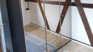 A room with a mirrored wardrobe, wooden beams, a patterned rug, and a framed artwork on the wall. - "VILLA HI" apartment parking space included  (Weesen)