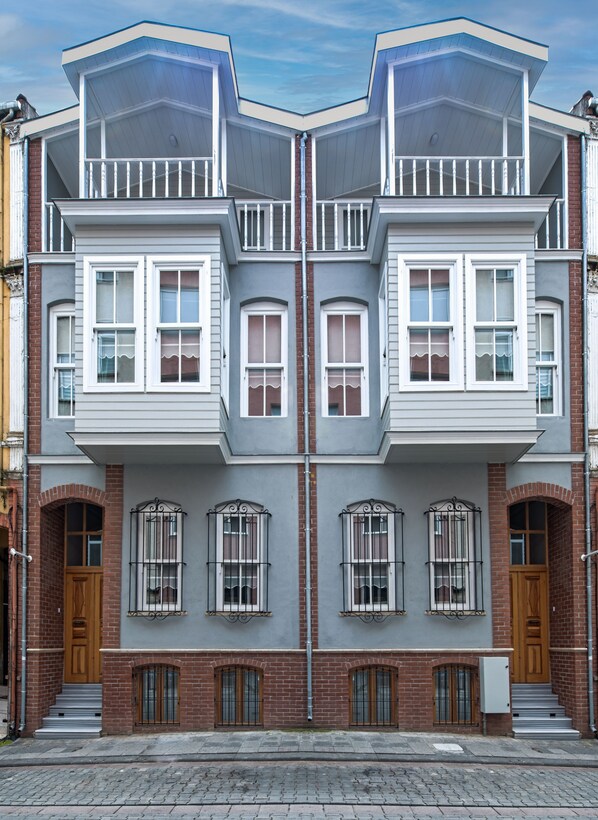 A symmetrical building with a central entrance, two upper floors with dormer windows, and a brick facade.