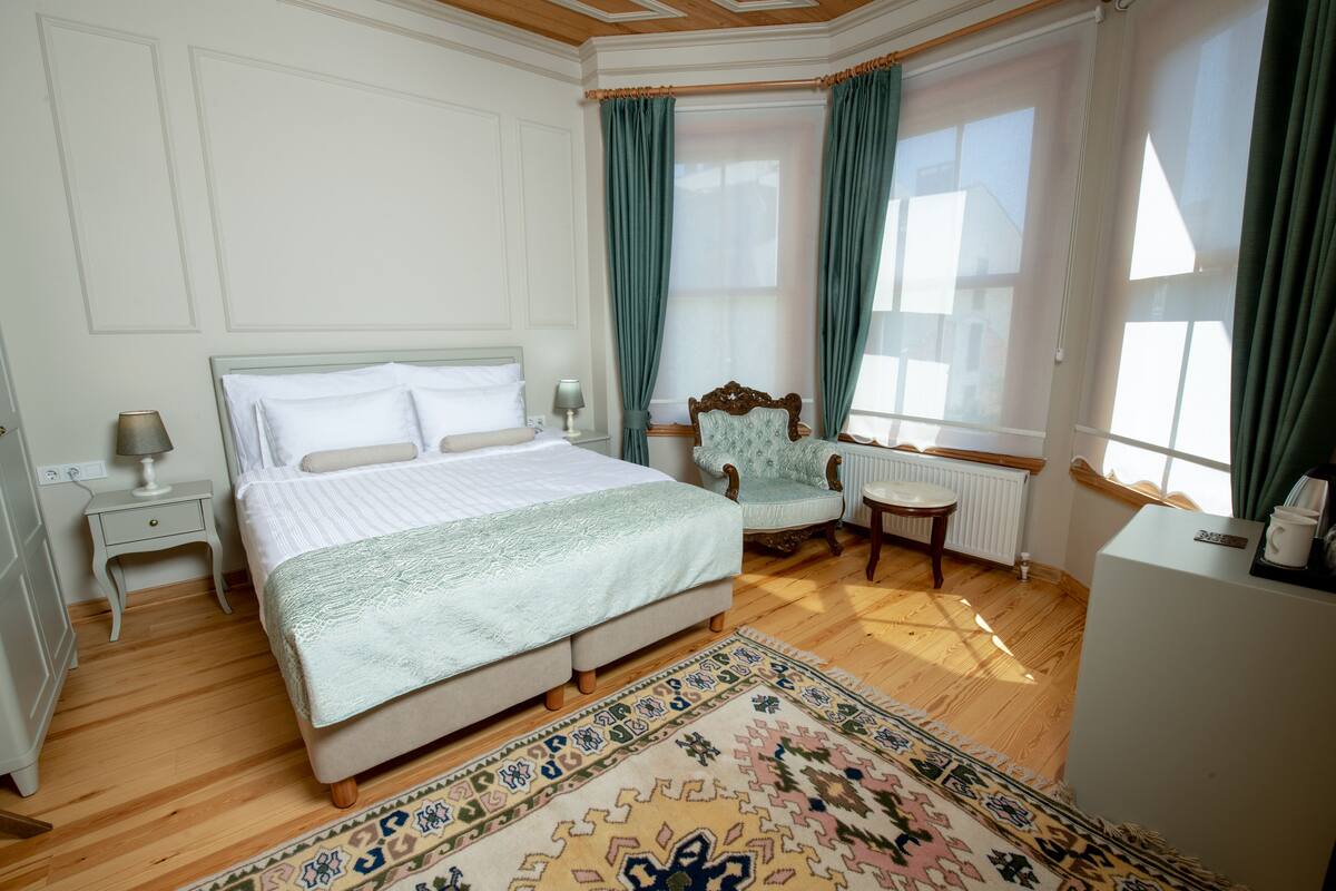 Een slaapkamer met een groot bed, een stoel, een bureau en een radiator.