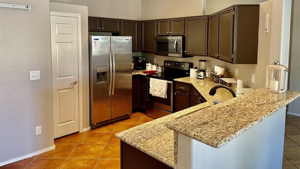 A kitchen with a stainless steel refrigerator, a microwave, an oven, and a granite countertop. - Great location close to Downtown Gilbert! Home features pool. (Gilbert)