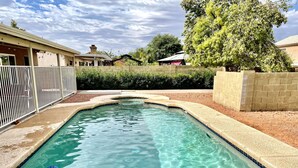 A rectangular swimming pool with clear blue water, surrounded by a low brick wall and a white fence. - Great location close to Downtown Gilbert! Home features pool. (Gilbert)