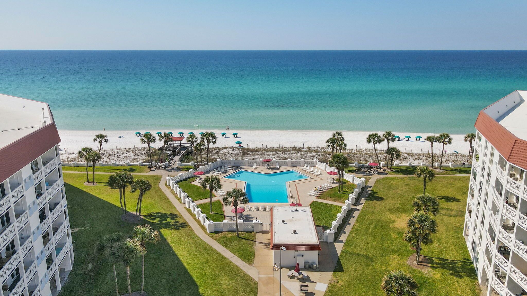 A hotel with a pool, beach, and ocean view.