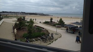 Une vue d’une promenade en bord de mer, avec un chemin pavé, des vélos et quelques personnes qui se promènent.