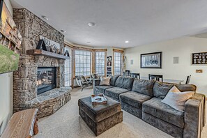 A cozy living room with a stone fireplace, a large sectional sofa, and a dining area with a wooden table.
